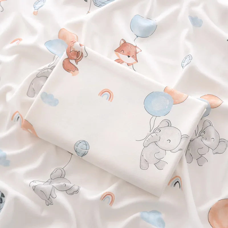 White lightweight cotton baby swaddle blanket with pastel animal and balloon prints for infants