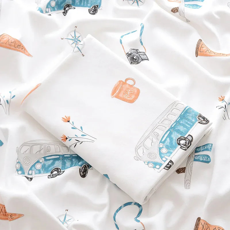 White lightweight cotton baby swaddle blanket with blue and orange travel-themed prints for newborns