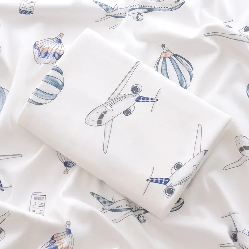 White lightweight cotton baby swaddle blanket with blue airplane and balloon print for newborns
