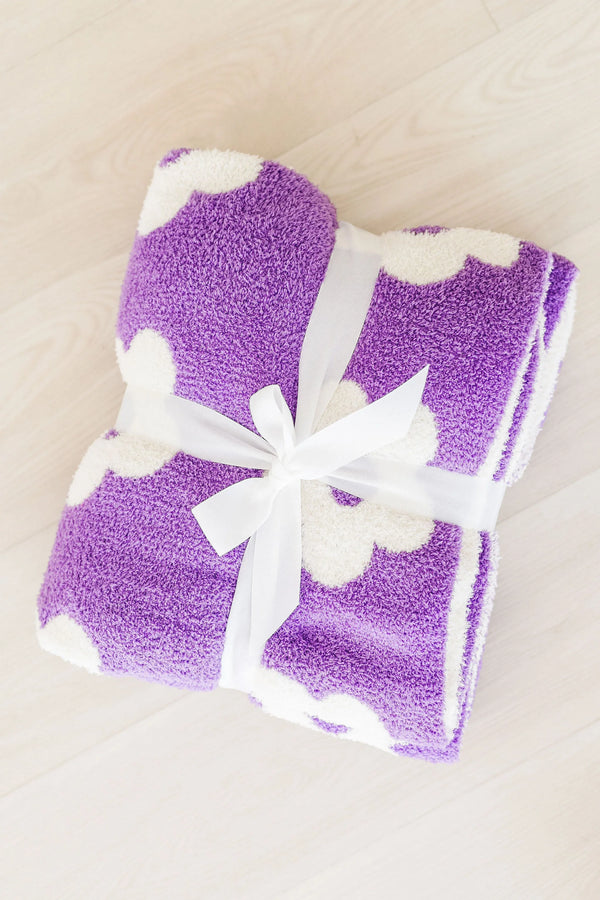 Lilac flower throw blanket for girls folded and tied with white ribbon on wooden floor