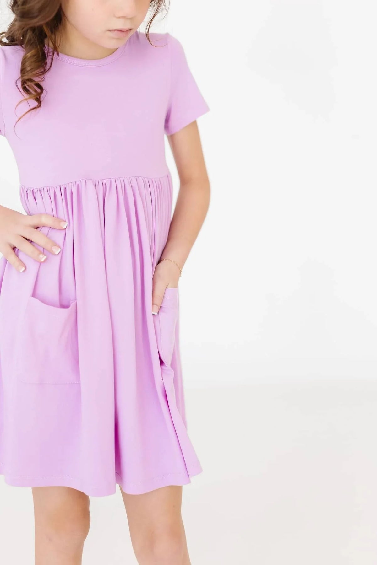Girl wearing lilac twirl dress for girls with short sleeves standing with hands in pockets