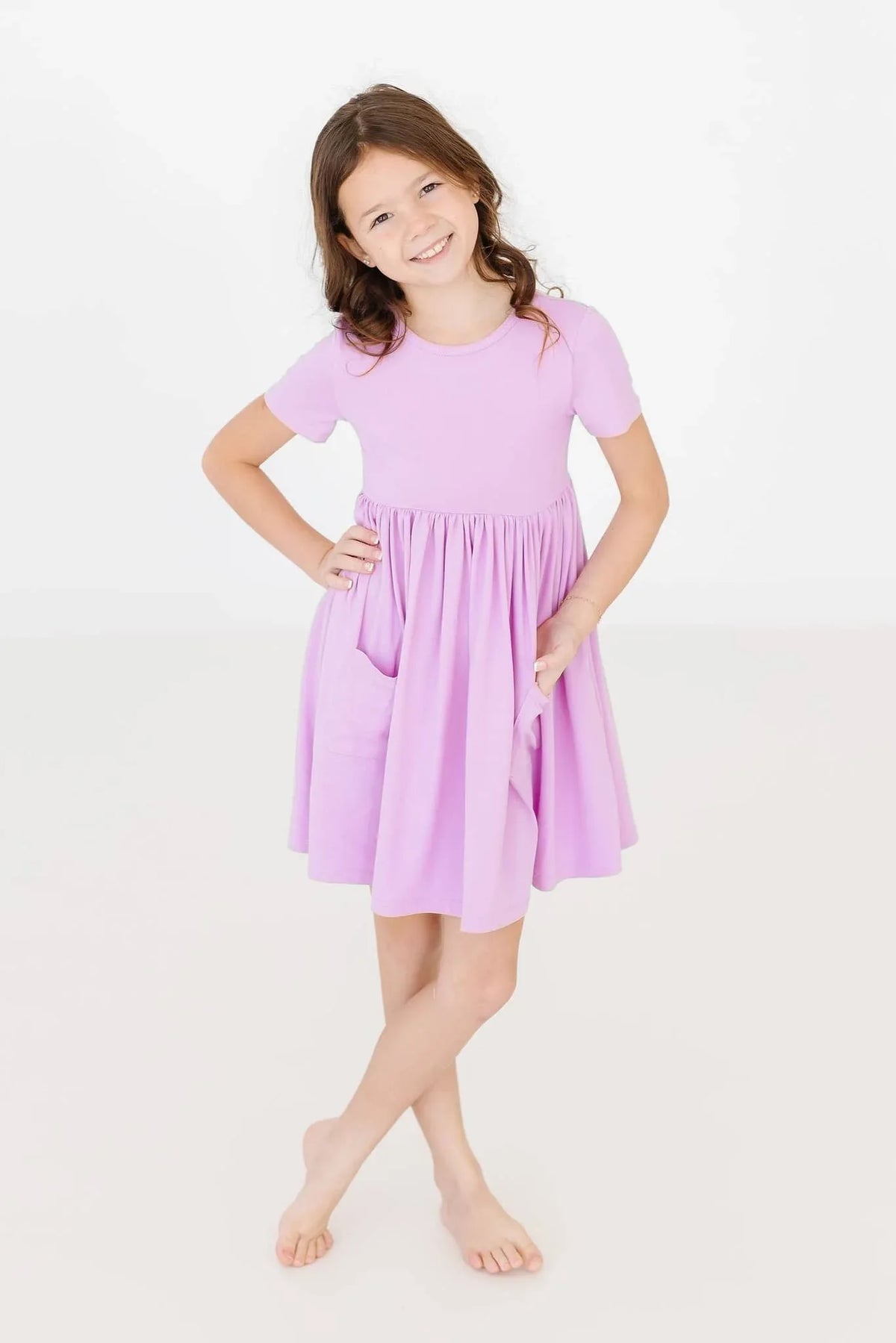 girl wearing lilac twirl dress for girls with short sleeves standing barefoot smiling