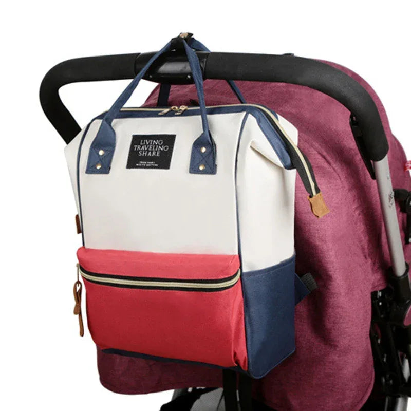 multifunctional insulated diaper bag in white red and navy hanging on stroller handle for babies and kids