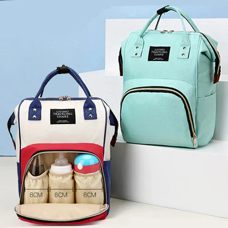 Multifunctional insulated diaper bag in light blue and red white with storage pockets holding baby bottles