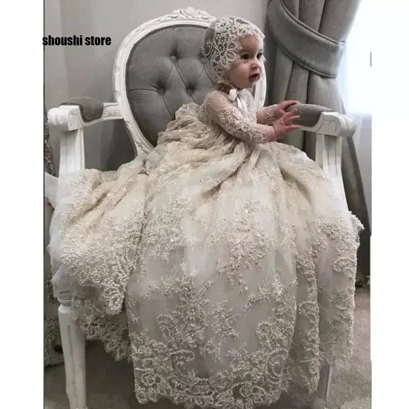baby girl wearing a luxury lace christening gown and matching bonnet sitting on a white vintage chair