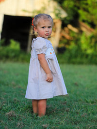 Fall Thanksgiving Pumpkin Embroidery Smock Plaid Girls Dress worn by a young girl outdoors.
