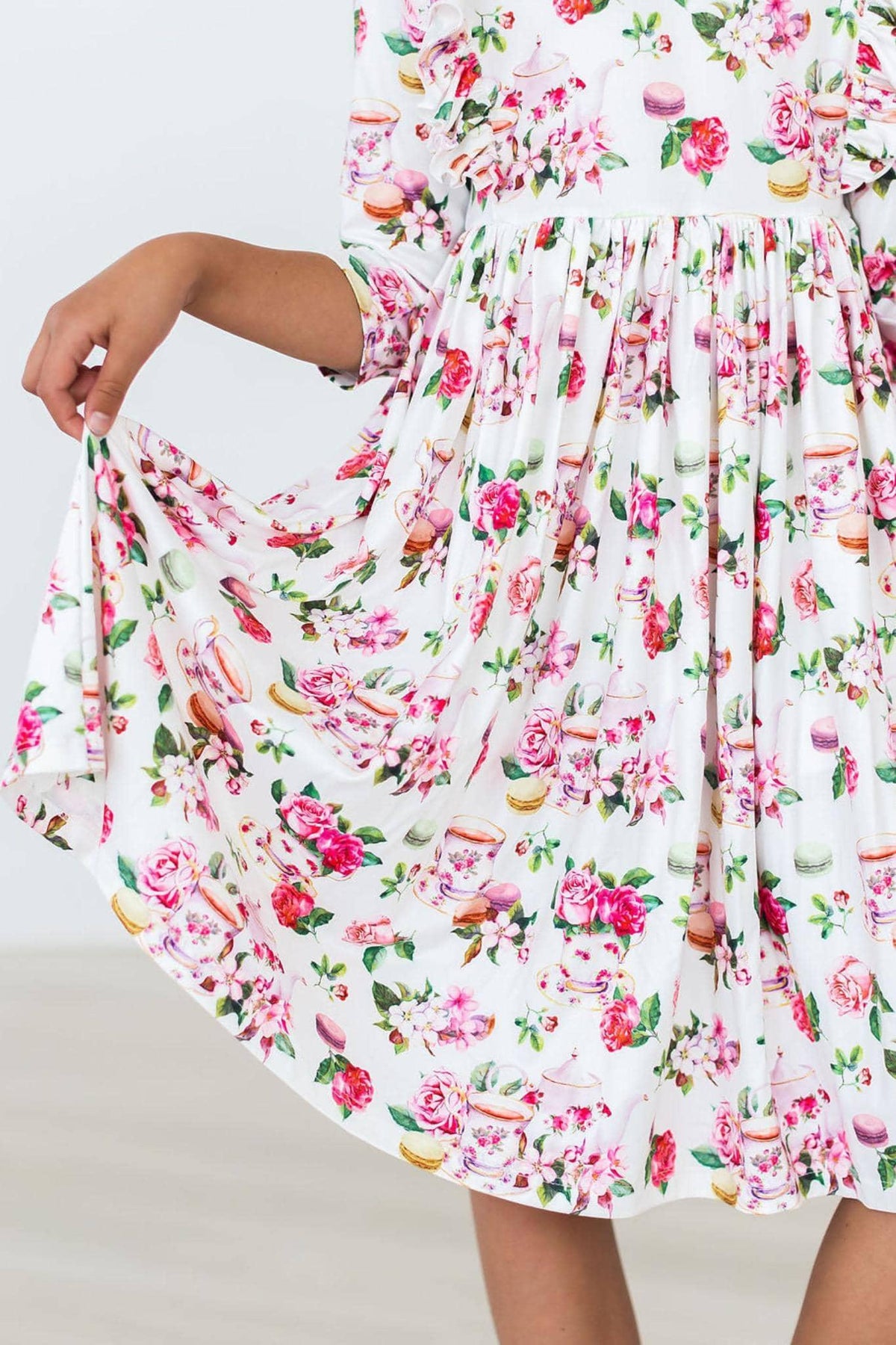 young girl wearing white floral ruffle twirl dress holding the skirt out to twirl