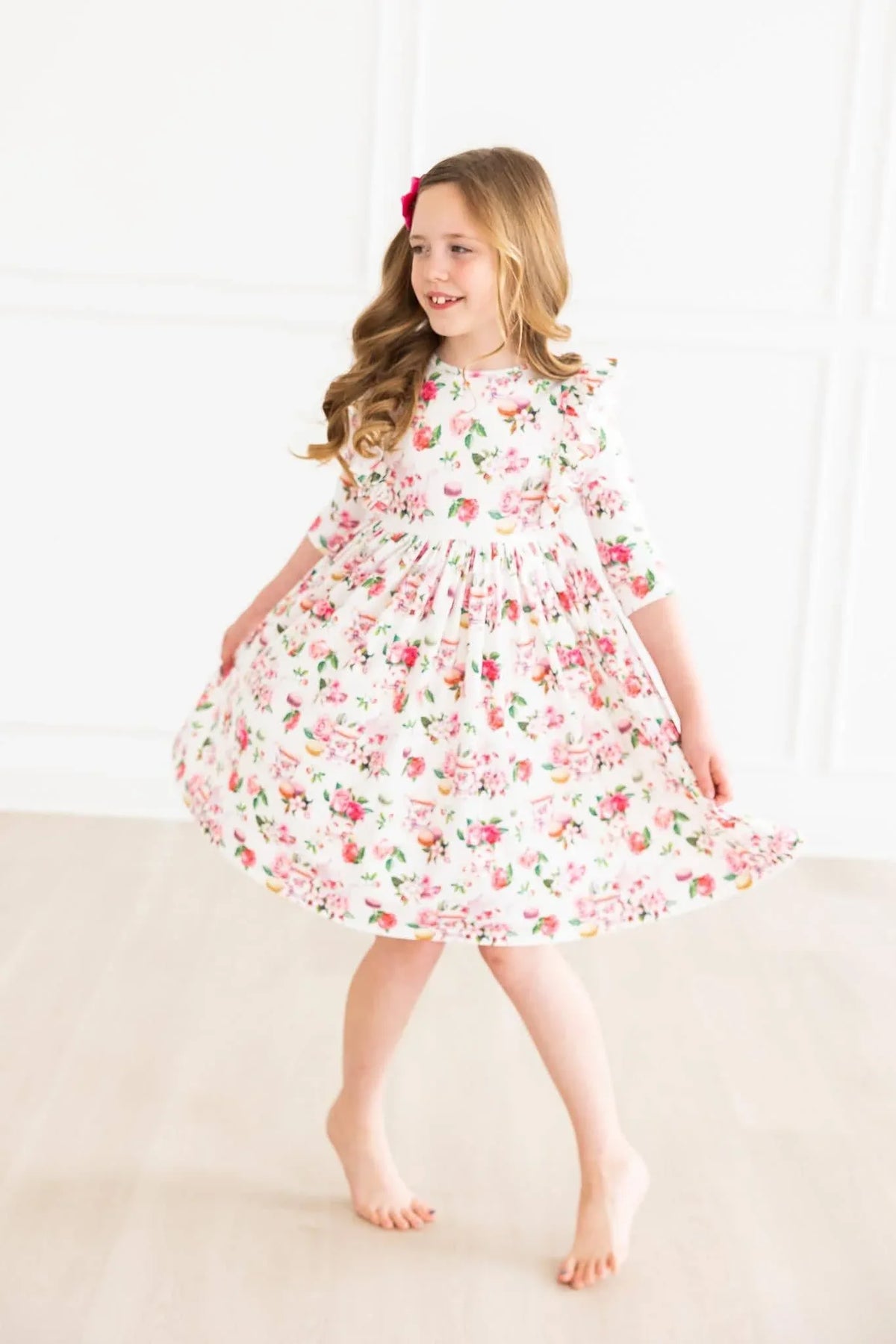 young girl wearing white floral ruffle twirl dress 3/4 sleeves spinning indoors