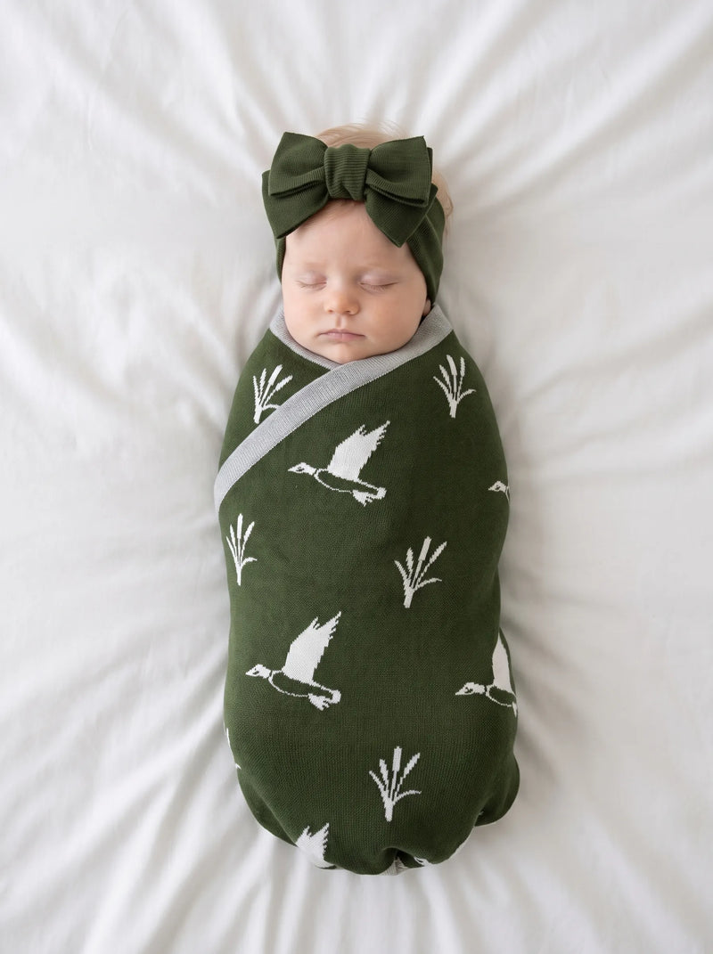 Newborn swaddled in green mallard duck jacquard knit baby blanket on white bedding