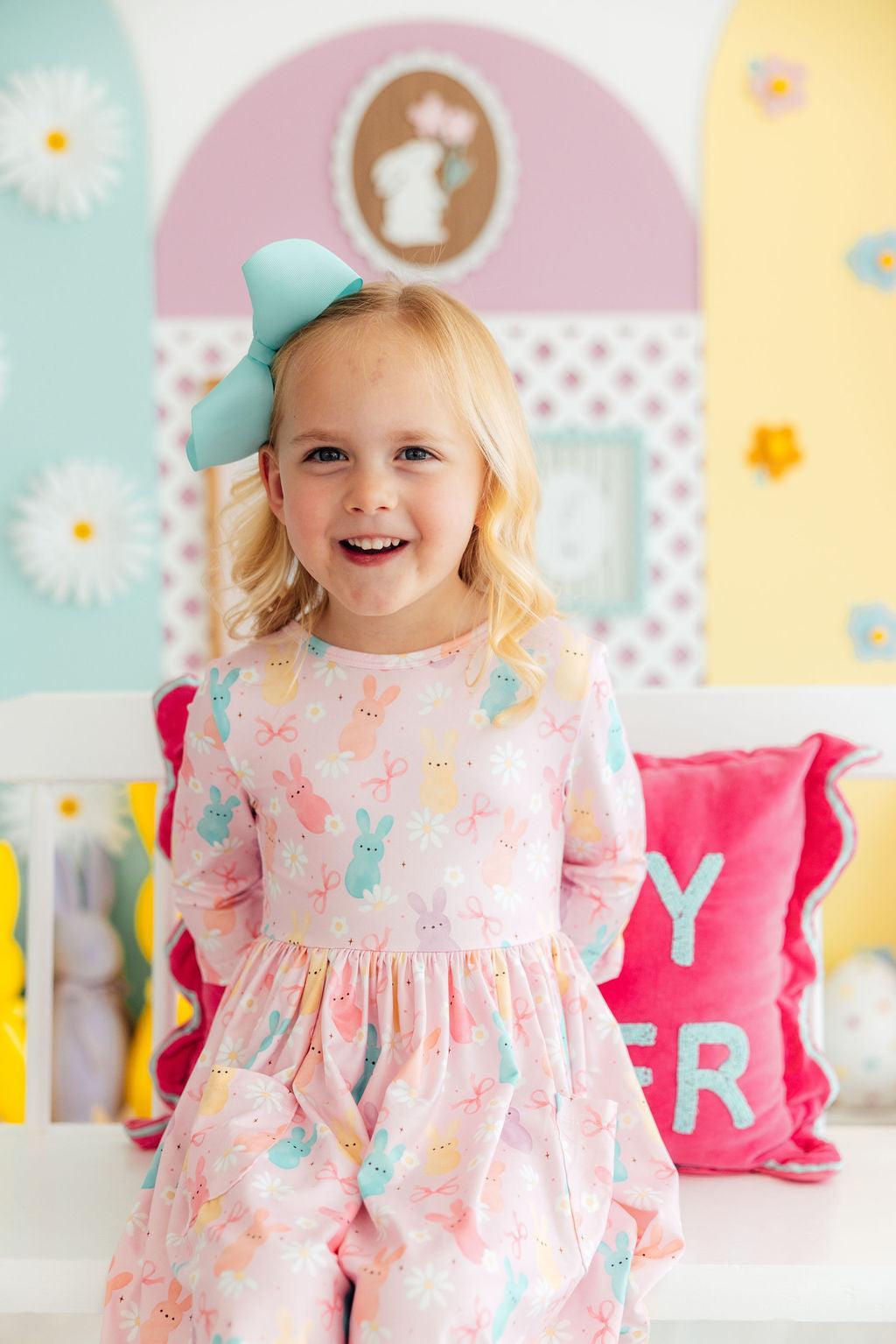 Preppy Peeps 3/4 Sleeve Pocket Twirl Dress worn by a smiling toddler in pastel bunny print with teal bow.