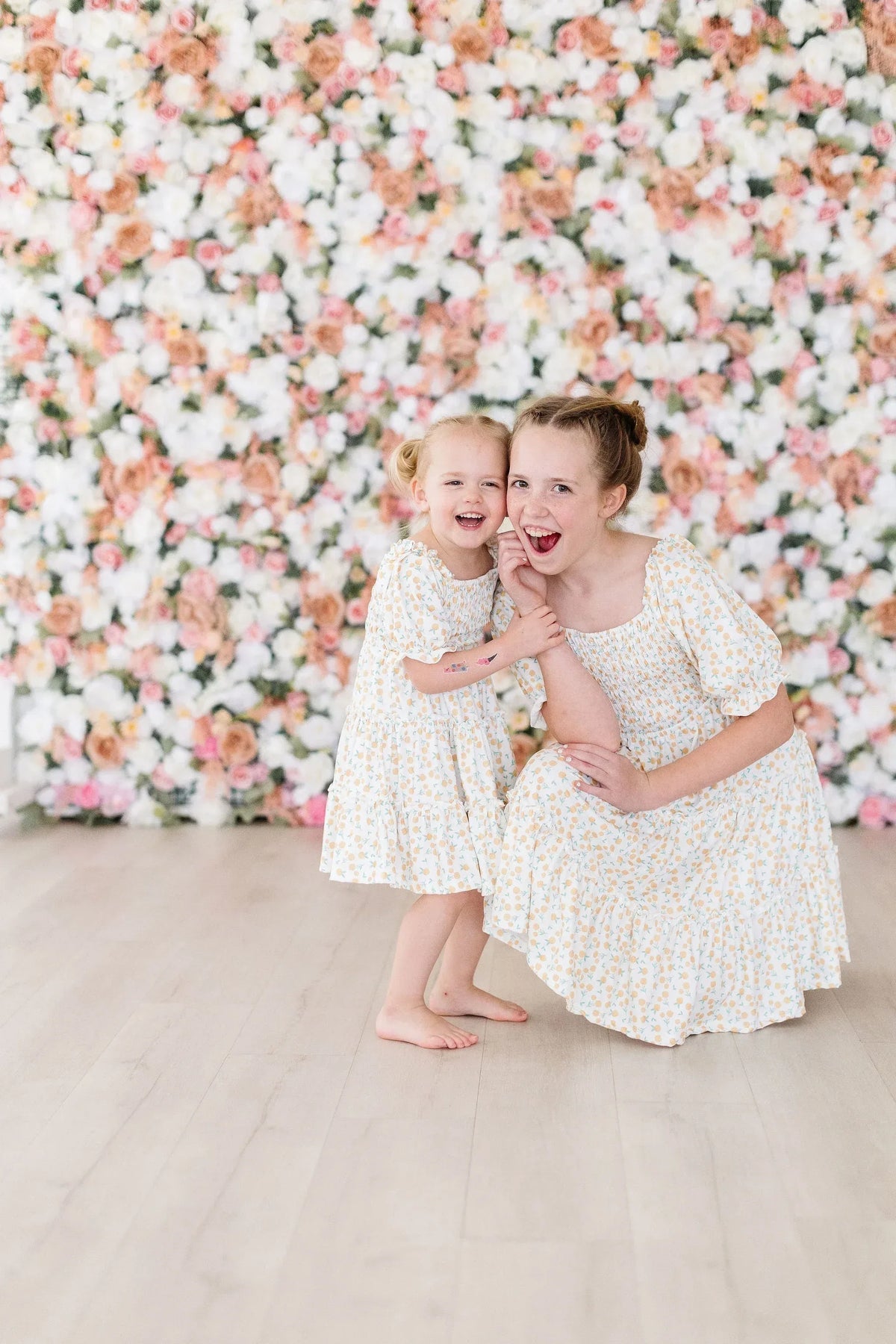 Little girl and woman wearing marigold smocked dress smiling and posing together indoors