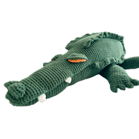 Large green crocheted crocodile stuffed animal with textured back, white teeth, and orange eye detail.
