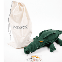 Large green crocheted crocodile with toothy face and ridged back, displayed next to a beige fabric storage bag.