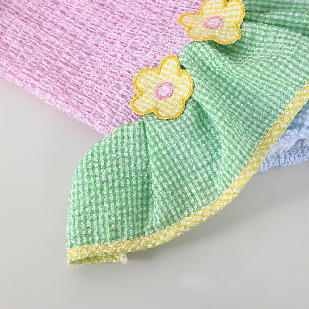 pink and green babies matching seersucker swimsuits for siblings with yellow flower accents and ruffled edges