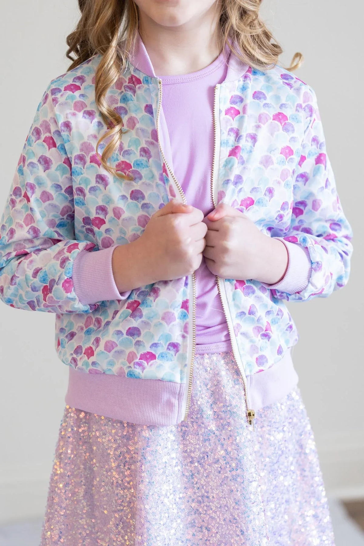 girl wearing pastel mermaid satin jacket for girls with purple seashell pattern and pink cuffs