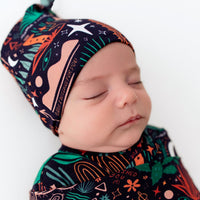 The SoftKnot Cap Desert Cactus (Midnight) on a sleeping newborn; navy bamboo cap with desert prints.
