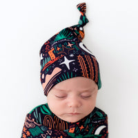Sleeping baby wearing Desert Cactus Midnight SoftKnot Cap, a cozy bamboo newborn hat with a knot.