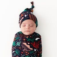 Newborn wearing The SoftKnot Cap Desert Cactus Midnight, navy knot cap with colorful desert-print pattern.