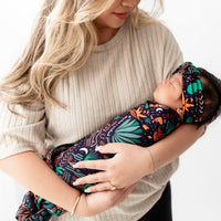 Baby wearing Desert Cactus Midnight SoftKnot Bow head-wrap, cradled by mom.