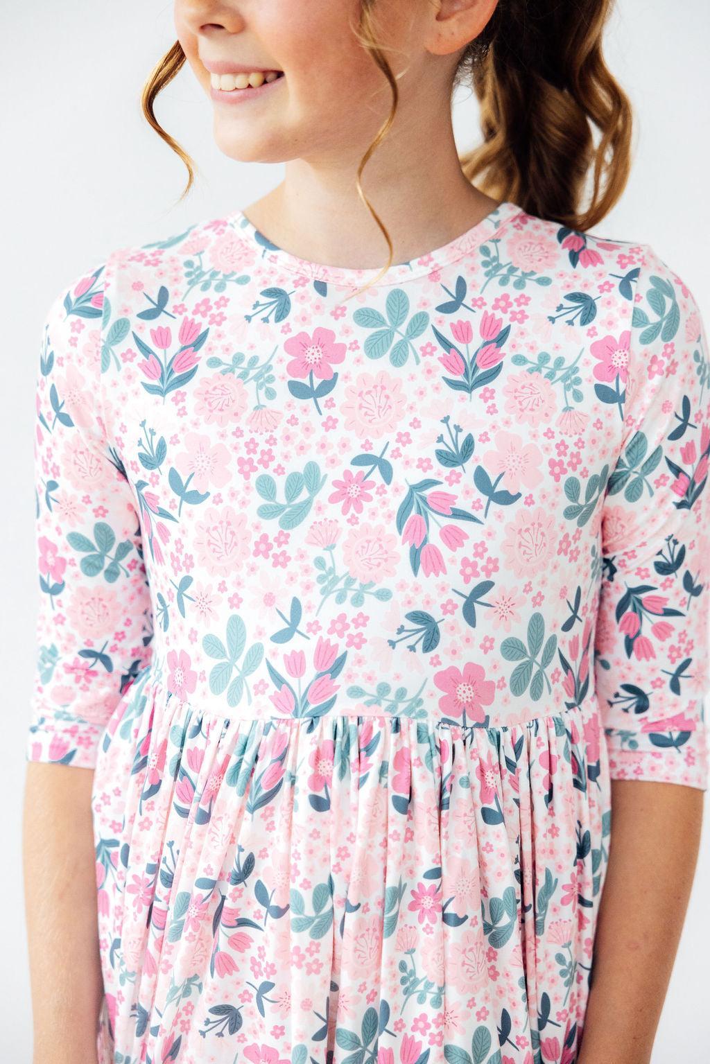 Close-up of a girl wearing the Softly Blooming 3/4 Sleeve Pocket Twirl Dress by Mila & Rose®, showcasing the beautiful floral pattern and soft fabric.