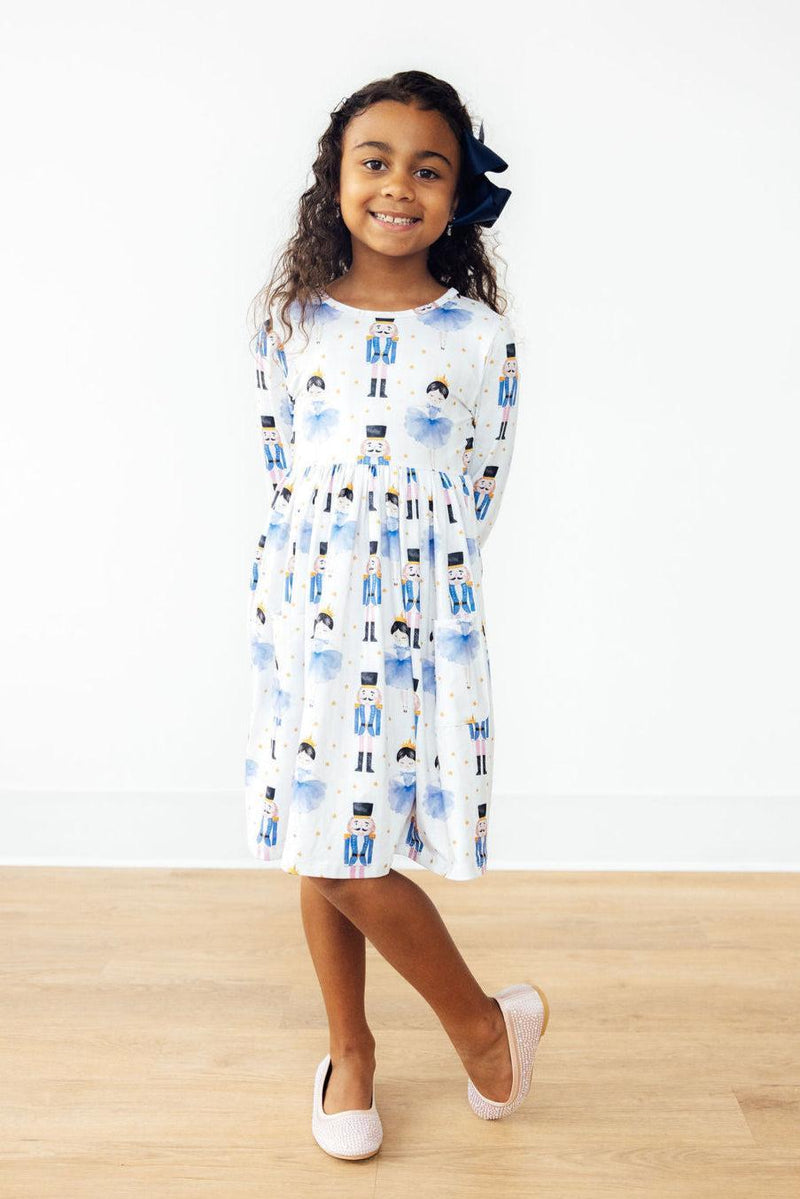 Smiling girl posing in the Waltz of the Snowflakes L/S Pocket Twirl Dress, showcasing the beautiful design and playful features.