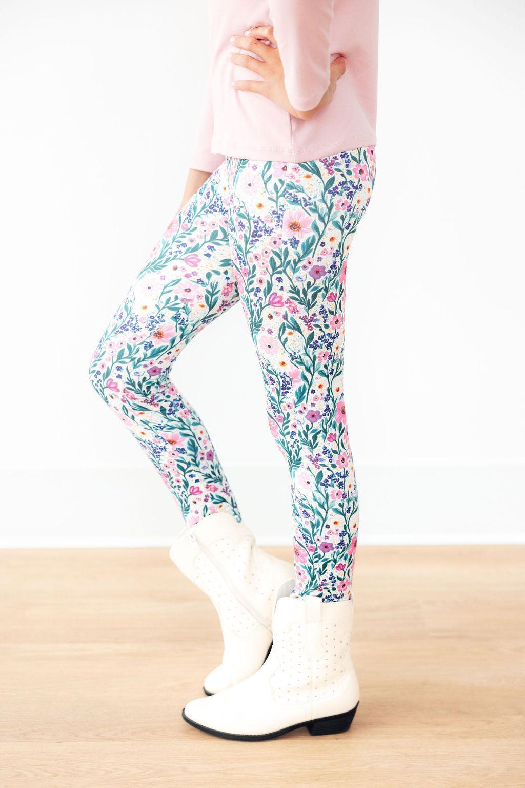 Vivid Garden Leggings featuring a colorful floral design, styled with a pink top and white boots, perfect for stylish athleisure wear.