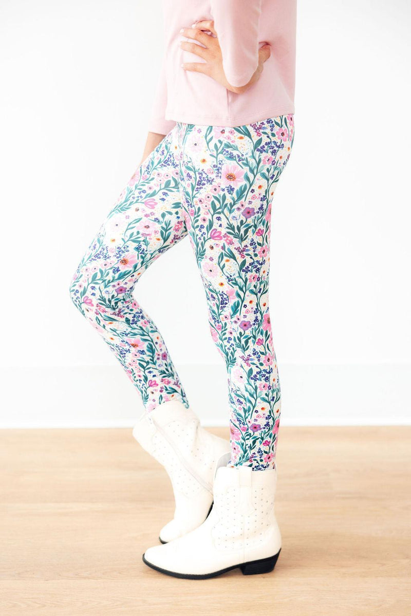 Vivid Garden Leggings featuring a colorful floral design, styled with a pink top and white boots, perfect for stylish athleisure wear.