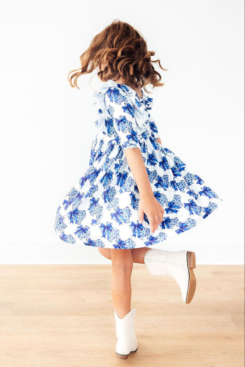 A happy girl spins joyfully in the Lone Star 3/4 Sleeve Ruffle Twirl Dress, highlighting its full-circle skirt that’s perfect for twirling fun, paired with cowboy boots.