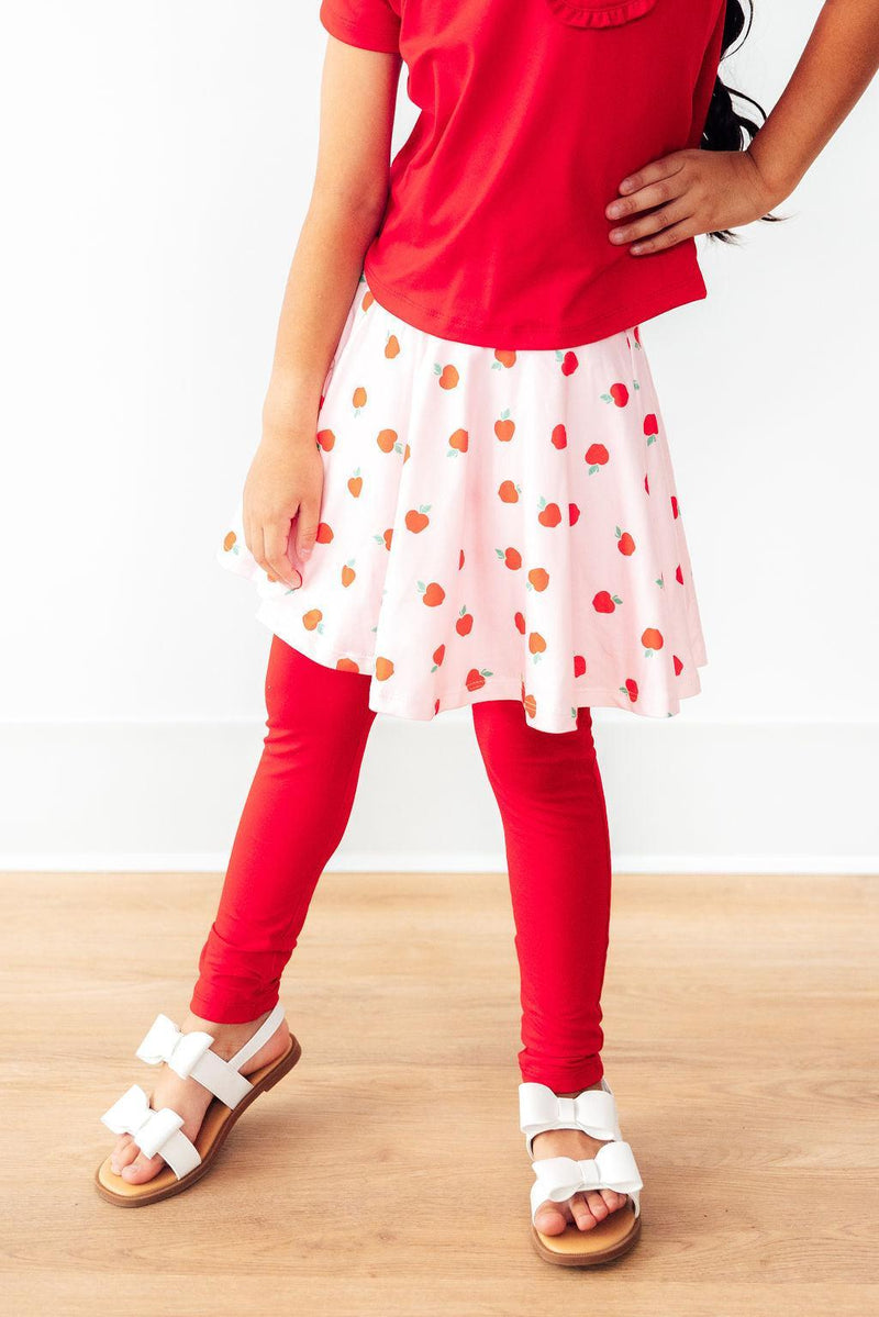 Close-up of a girl posing confidently in An Apple a Day Twirl Skeggings for Girls, highlighting the cheerful skirt and legging combination perfect for everyday wear. Ideal skeggings for girls.