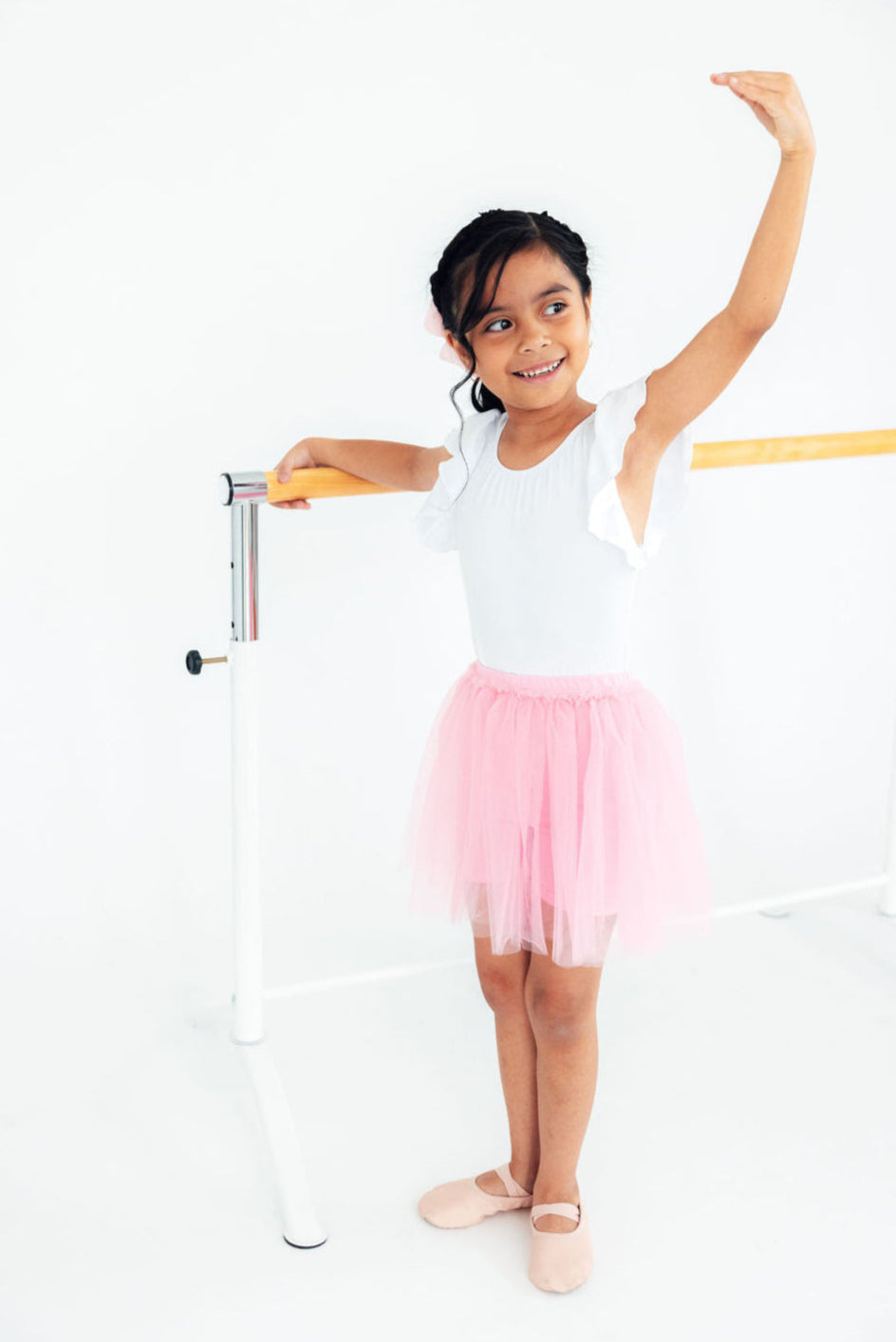 Girl practicing ballet in pink tutu shorts for girls, showcasing the flouncy overlay that adds twirl-worthy fun and playground practicality.