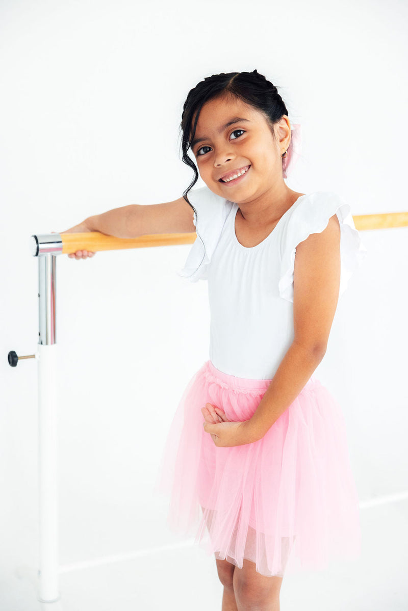 Smiling girl wearing pink tutu shorts for girls, perfect for dance class, featuring a flouncy overlay for playful movement.