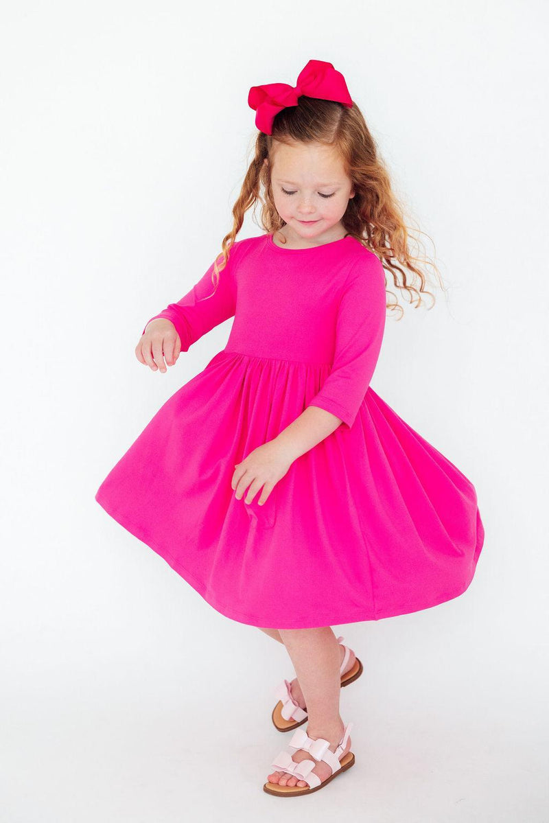 Adorable girl twirling in a Hot Pink 3/4 Sleeve Pocket Twirl Dress, showcasing a vibrant skirt, perfect for playful spins.