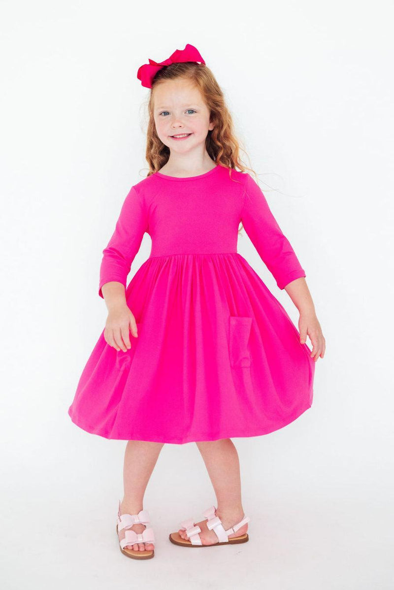 Charming girl displaying her Hot Pink 3/4 Sleeve Pocket Twirl Dress, complete with pockets, ready for her next adventure!