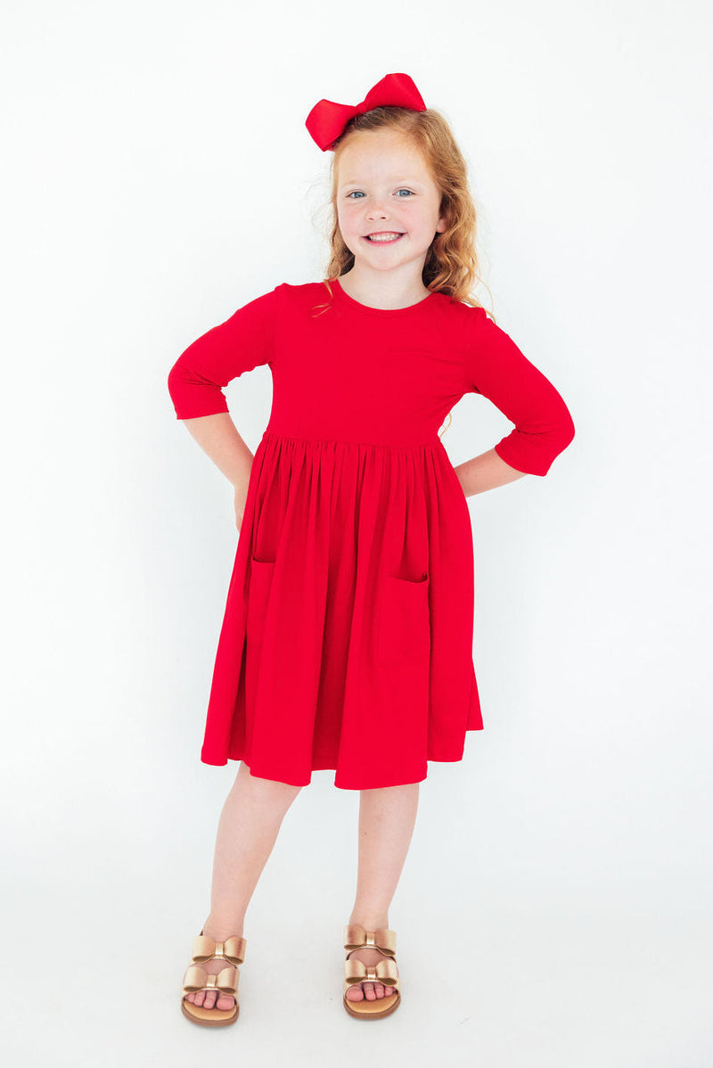 Happy child in a Red 3/4 Sleeve Pocket Twirl Dress from Mila & Rose, featuring a comfortable fit perfect for twirling and playful activities.