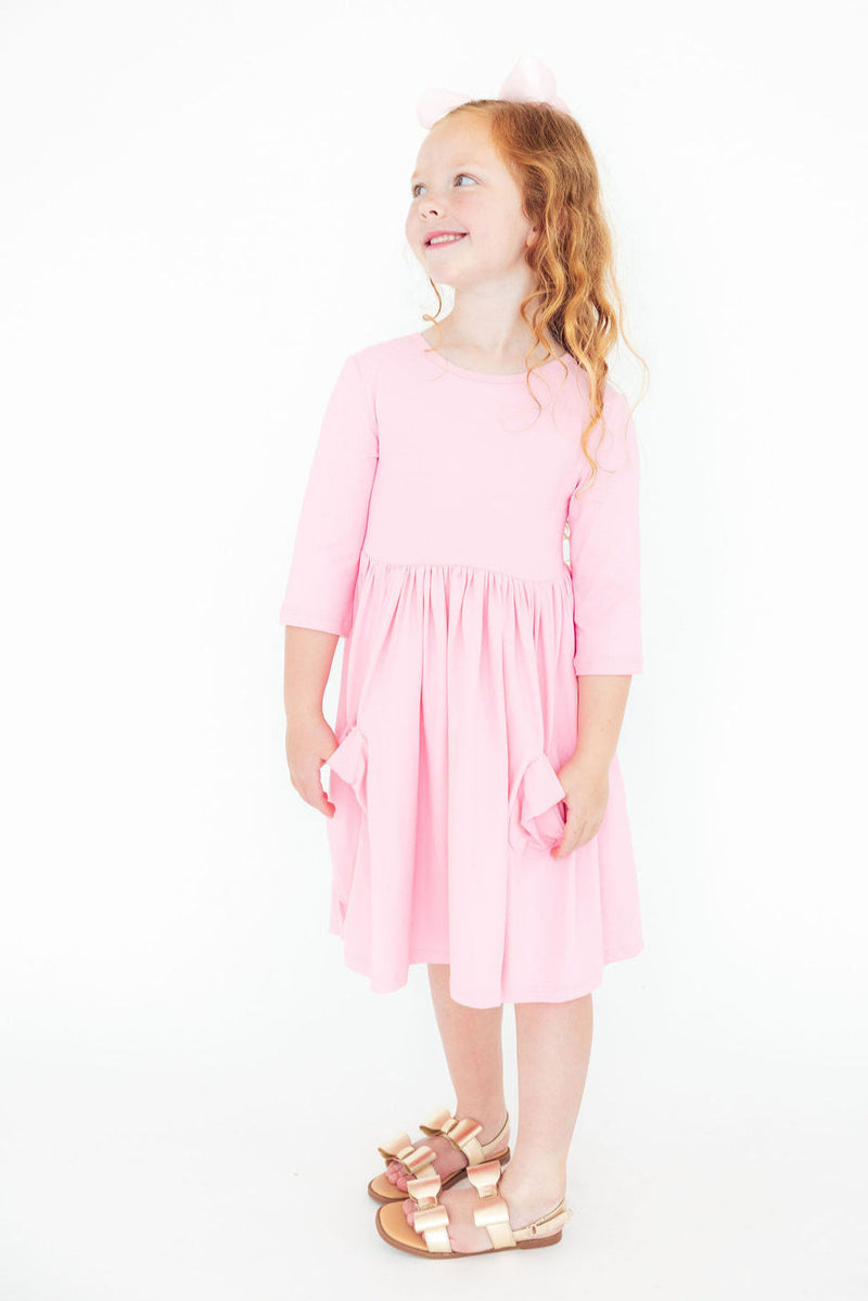 Girl wearing the Bubblegum Pink 3/4 Sleeve Pocket Twirl Dress, twirling and enjoying her playful adventures, embodying the fun spirit of the dress.
