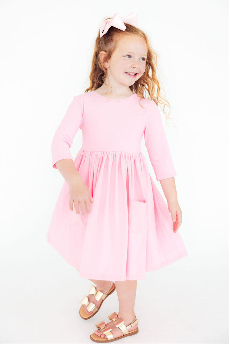 The Bubblegum Pink 3/4 Sleeve Pocket Twirl Dress for Girls with functional side pockets, perfect for holding treasures during playtime.