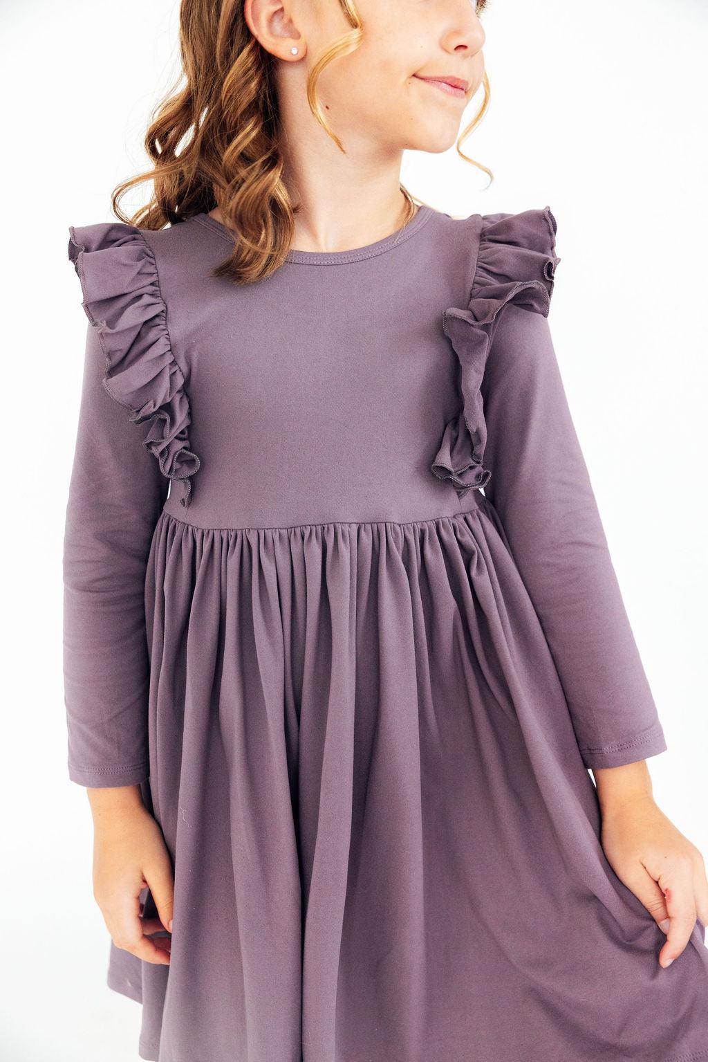 Close-up of a girl wearing the Vintage Violet Long Sleeve Ruffle Twirl Dress featuring ruffle details and a flowing skirt.
