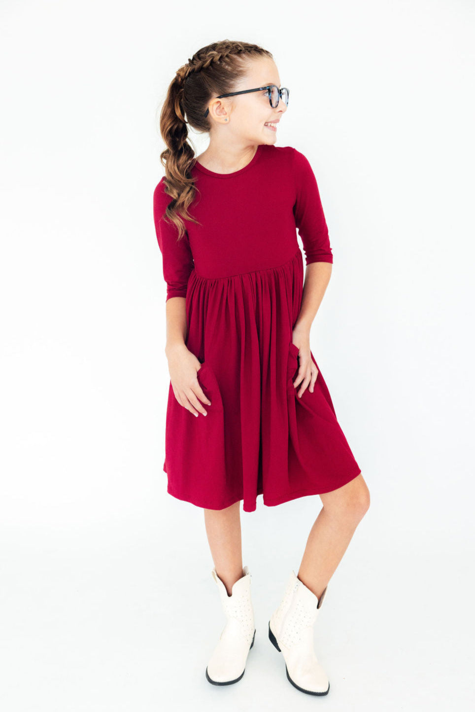 Girl smiling in a Burgundy 3/4 Sleeve Pocket Twirl Dress from Mila & Rose, featuring practical pockets and a soft, playful design.