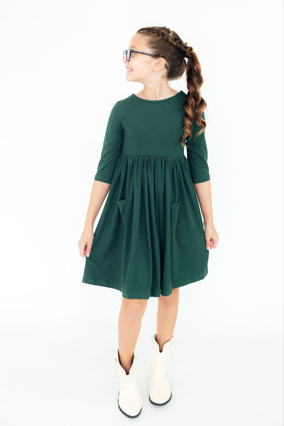 Girl wearing the Spruce 3/4 Sleeve Pocket Twirl Dress, smiling and posing with hands in pockets, showcasing the full-circle skirt and a fun, playful style.