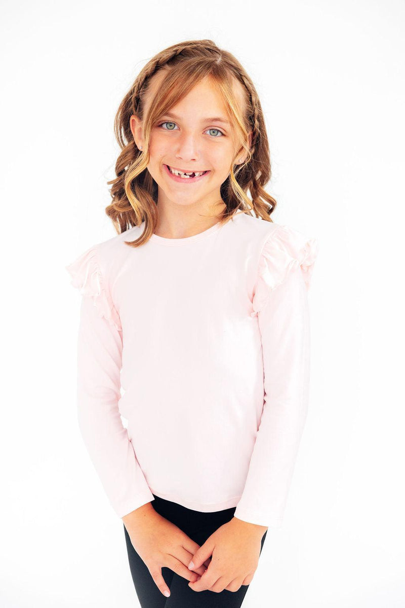 Charming child wearing the Petal Pink L/S Ruffle Tee by Mila & Rose ®, showcasing style and sweetness with cheerful ruffle details.