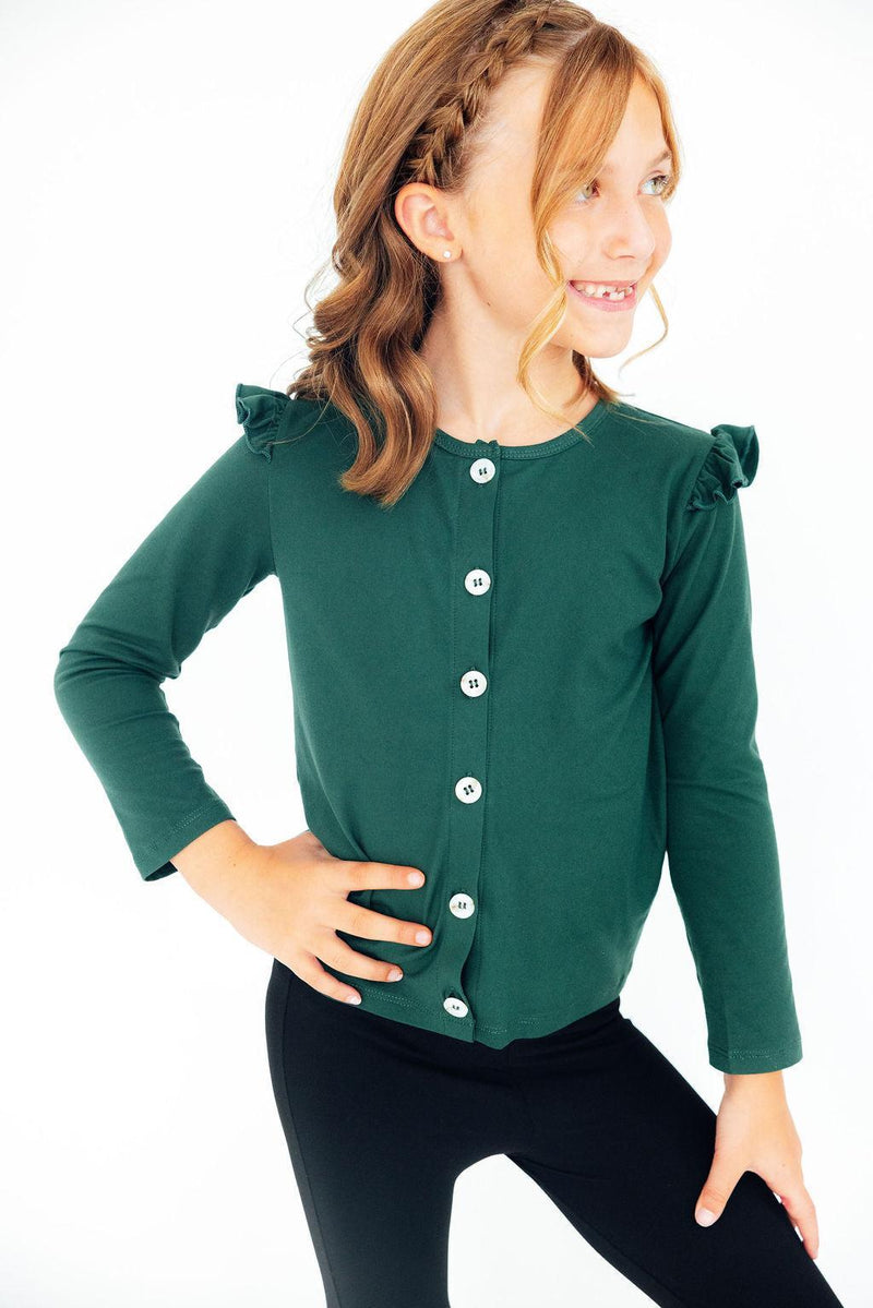 Happy girl modeling the Spruce Ruffle Cardigan with ruffle accents, showcasing its vibrant green color and comfortable fit, ideal for everyday wear.