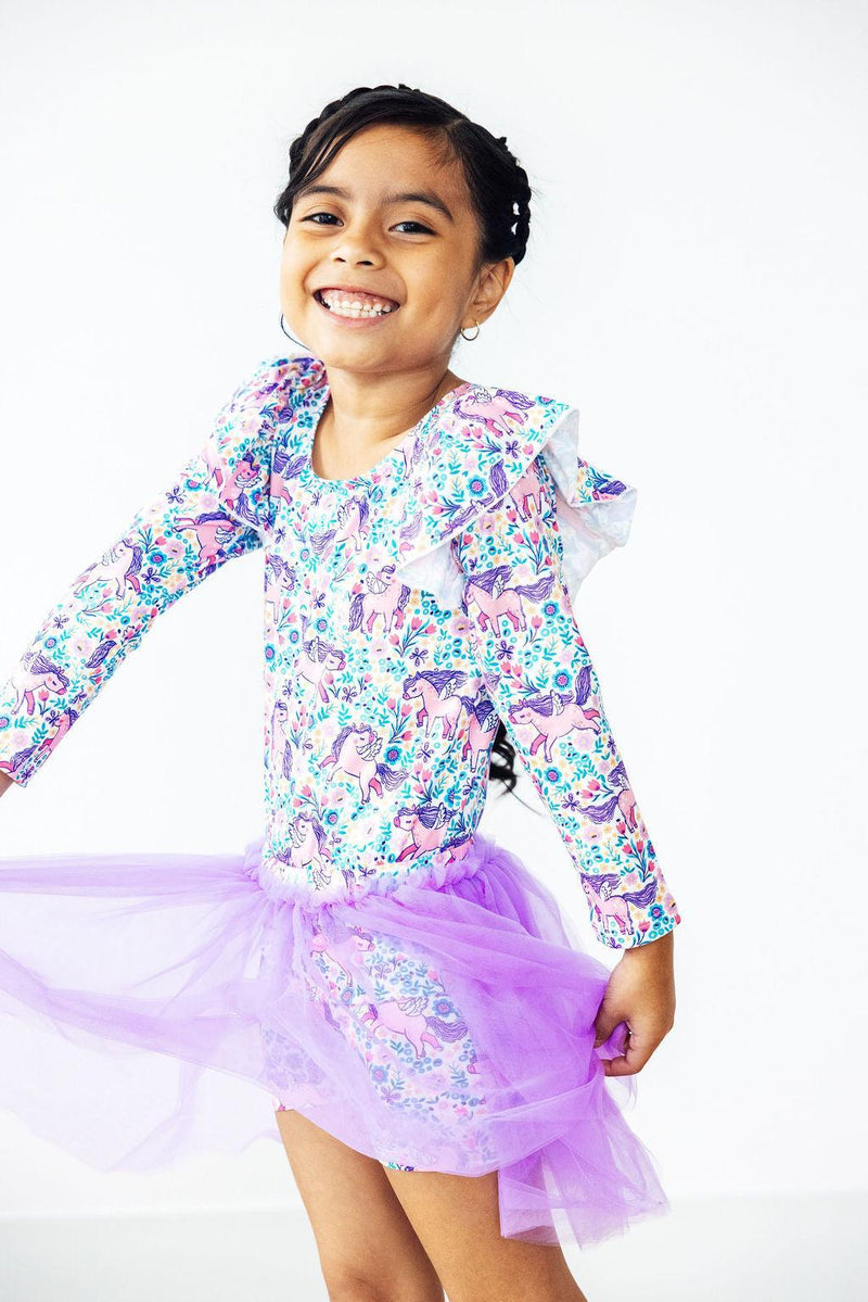 Close-up of a happy girl in Head in the Clouds Tutu Shorts, showcasing her colorful dance outfit and playful purple tutu while spinning.