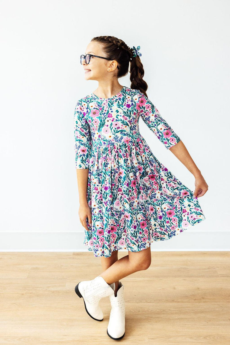 A girl twirling in the Vivid Garden 3/4 Sleeve Pocket Twirl Dress from Mila & Rose ®, capturing the full-circle skirt's movement and vibrant floral pattern.