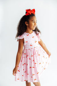 Close up of the Cherry Sweet Flutter Sleeve Twirl Dress for Girls, showcasing fabric and design.
