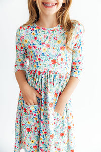 Girl wearing colorful floral 3/4 sleeve twirl dress with front pockets, designed for comfort and easy play.