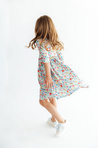 Child twirling in colorful floral 3/4 sleeve pocket dress with scoop back, perfect for school, play, and special occasions.