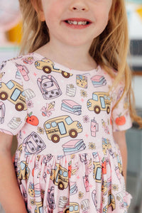 Playground Princess pink short-sleeve twirl dress on a smiling girl with school bus, backpack, and book print.