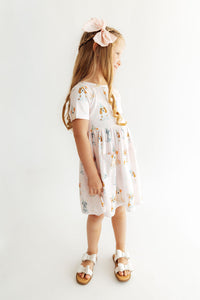 Girl wearing a pink short sleeve twirl dress with puppy print, front pocket, and matching bow. Designed for comfort and easy play.