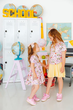 Two girls in Playground Princess Short Sleeve Pocket Twirl Dress twirl in a playroom with lockers and globes.