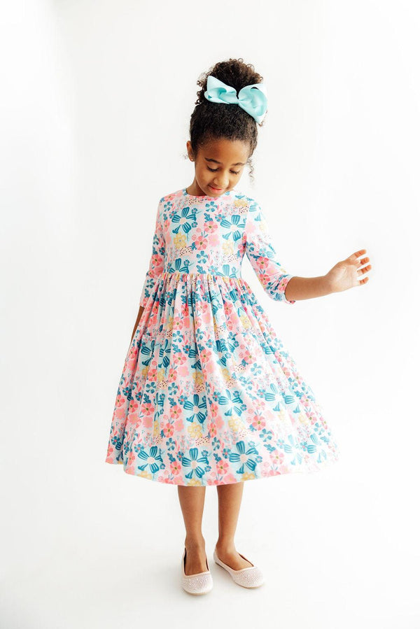 Girl in Floral Garden 3/4 sleeve twirl dress with pastel florals and teal bow.